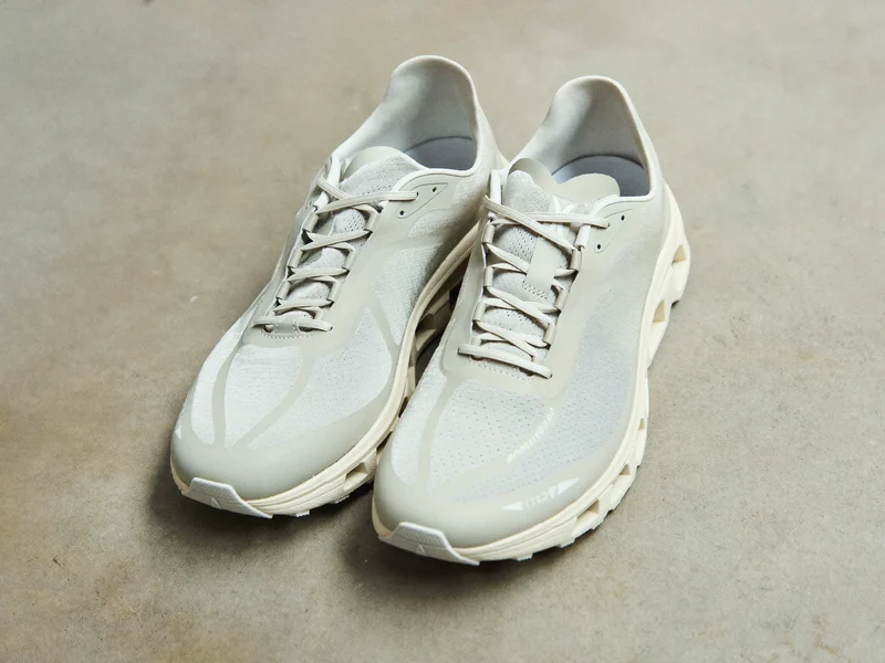 Hellgraue Mesh-Laufsneaker auf heller Betonfläche aus leicht erhöhtem Blickwinkel