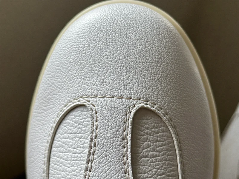 Nahaufnahme von Lederstruktur und feinen Nähten an der Kappe eines weissen Sneakers
